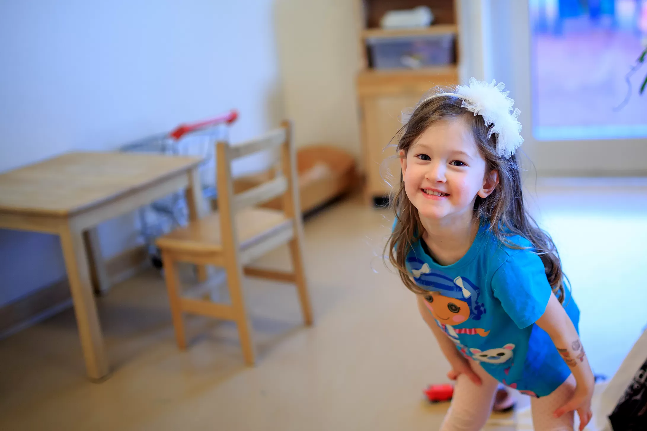 A smiling female preschool child in blue t-shirt posing